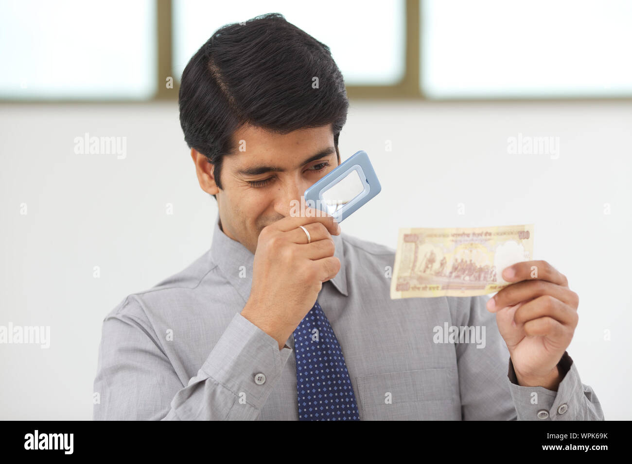 Businessman examining five hundred rupee note banknote with magnifying ...