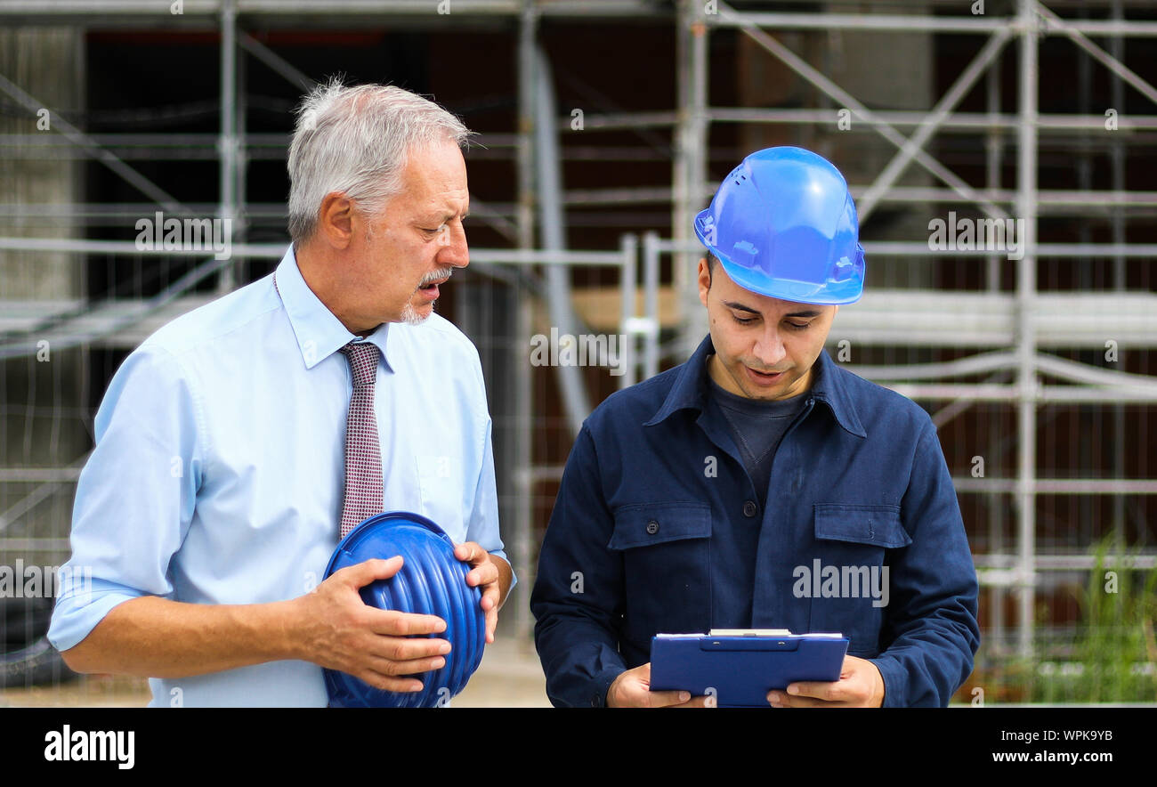 Two architect developers reviewing building plans at construction site Stock Photo