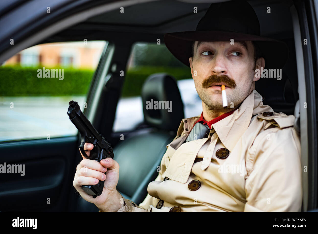 Detective readying his gun while waiting in his car Stock Photo