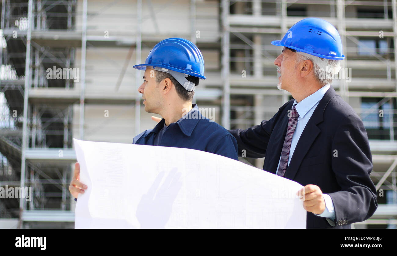 Two architect developers reviewing building plans at construction site Stock Photo