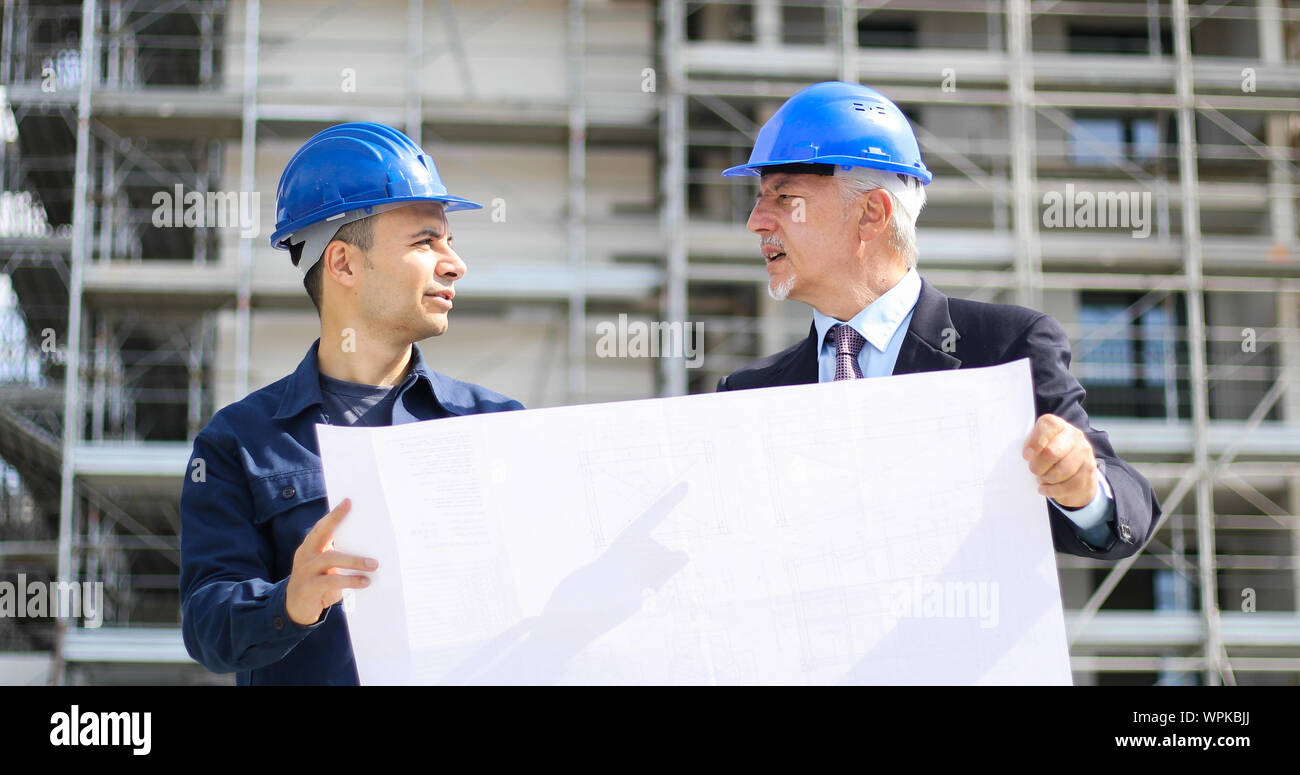 Two architect developers reviewing building plans at construction site Stock Photo