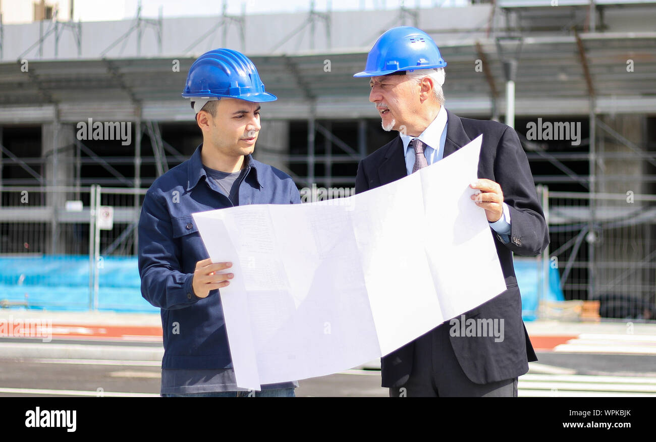 Two architect developers reviewing building plans at construction site Stock Photo