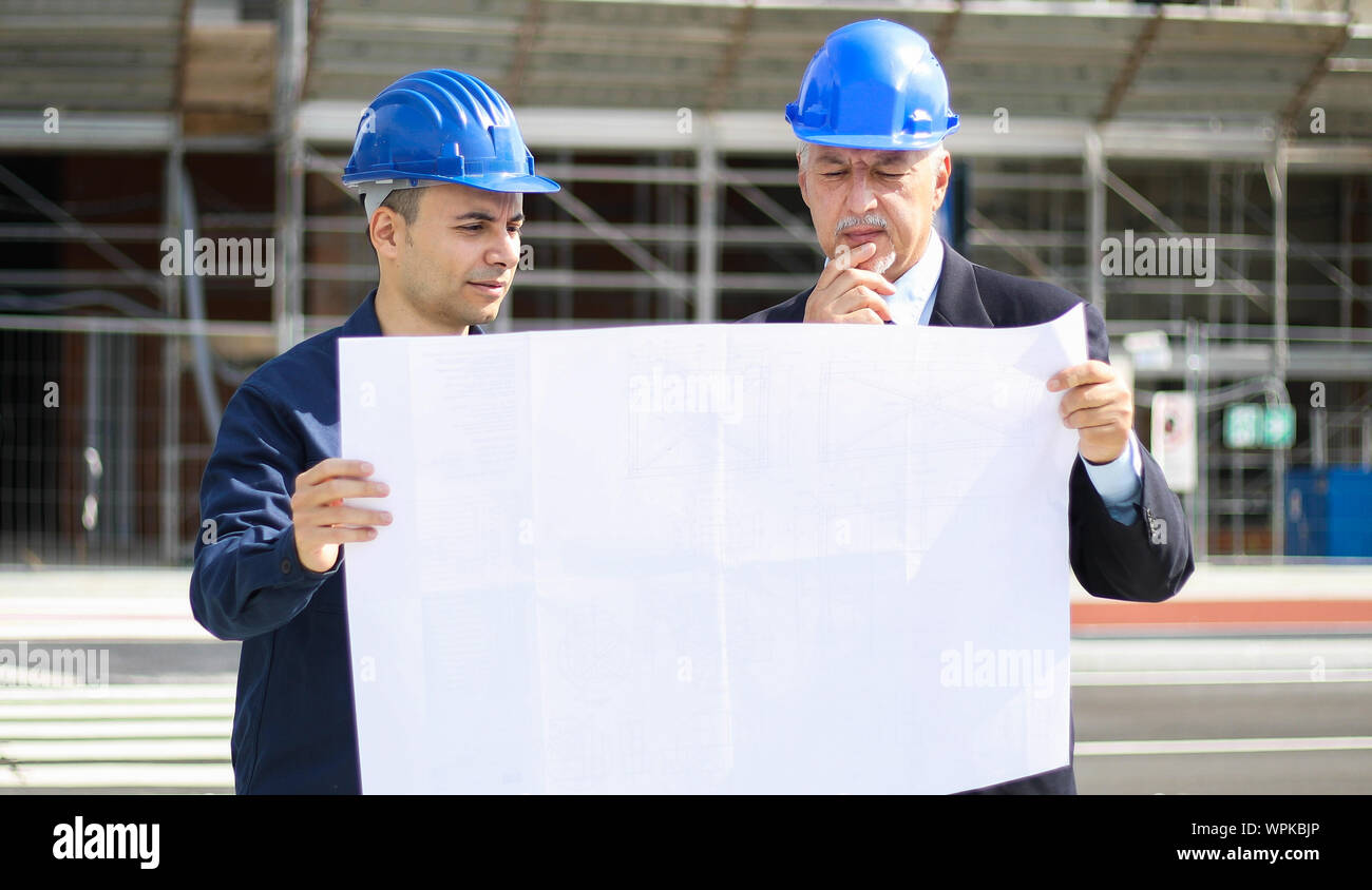 Two architect developers reviewing building plans at construction site Stock Photo