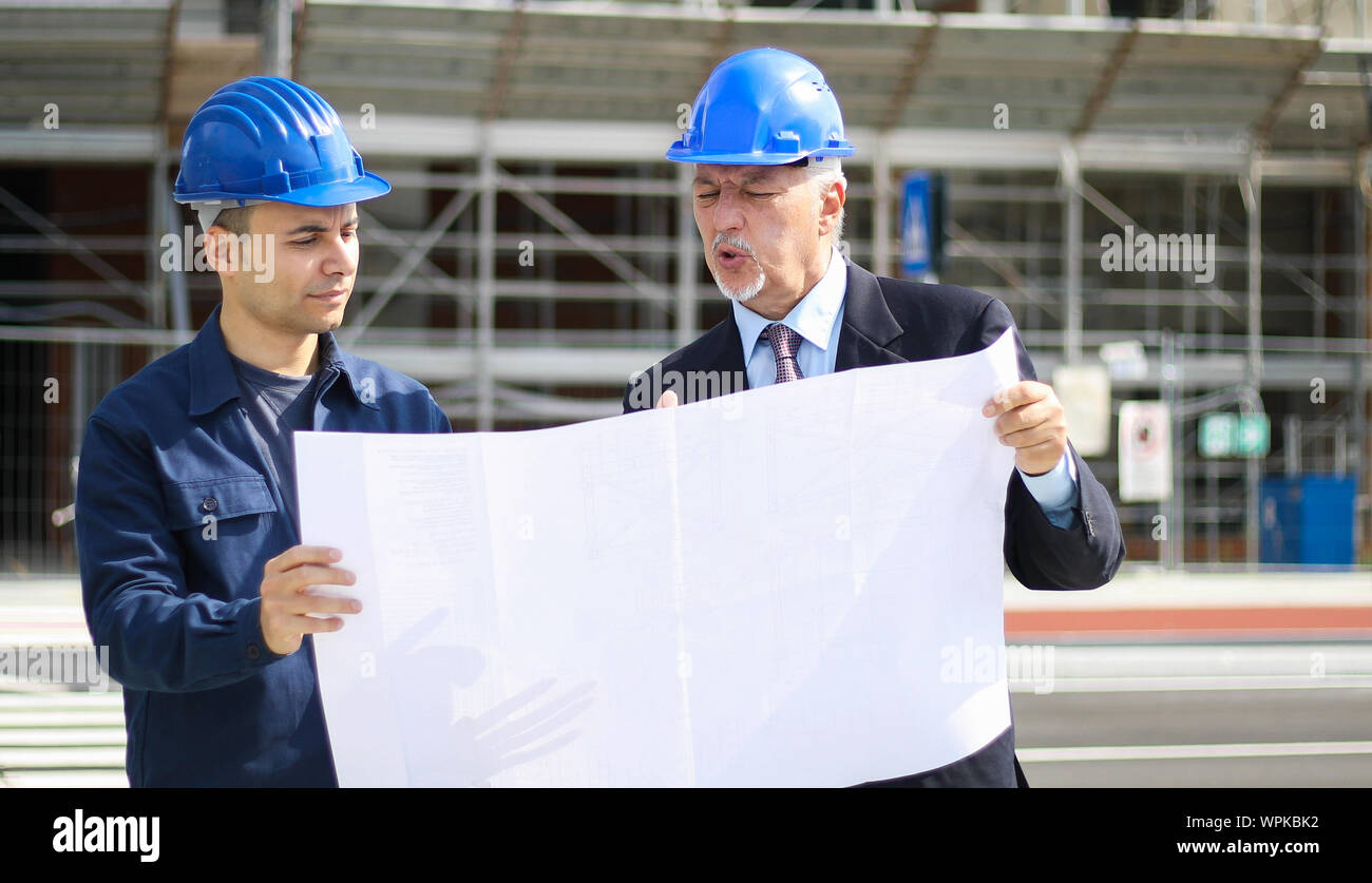 Two architect developers reviewing building plans at construction site Stock Photo