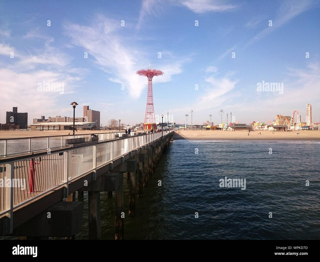 Pier Over Sea By Parachute Jump Against Sky Stock Photo