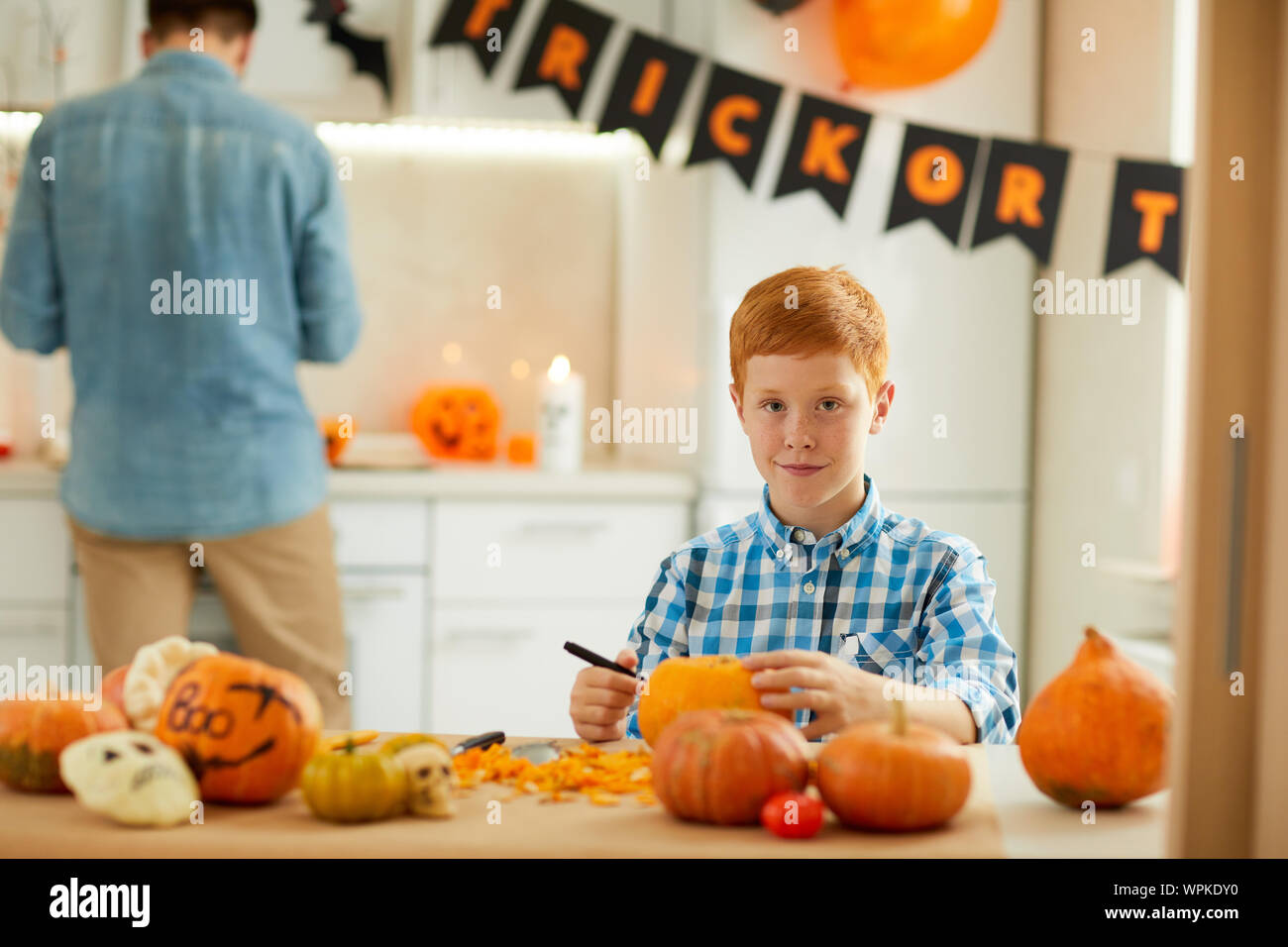 Portrait of little red haired boy carving pumpkin he making Jack O ...
