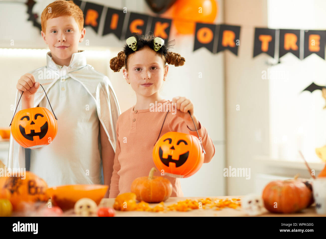 Portrait of two children dressed in costumes holding Jack O' Lanterns ...