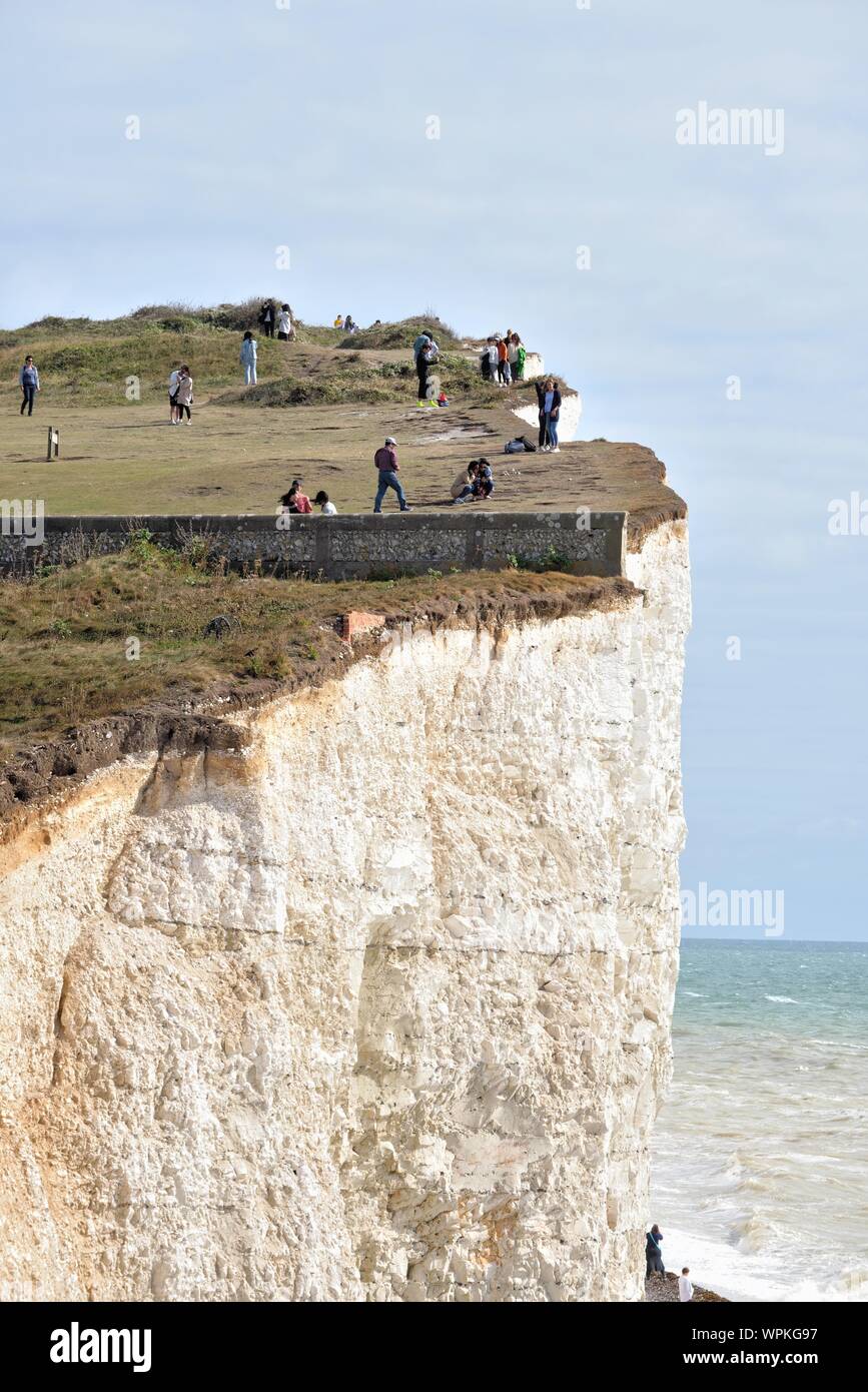 Young Korean tourists taking photographs standing on the edge of the chalk cliffs at Birling Gap Eastbourne East Sussex England UK Stock Photo