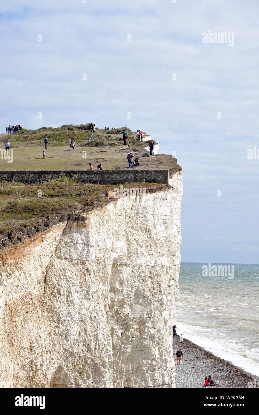Young Korean tourists taking photographs standing on the edge of the chalk cliffs at Birling Gap Eastbourne East Sussex England UK Stock Photo