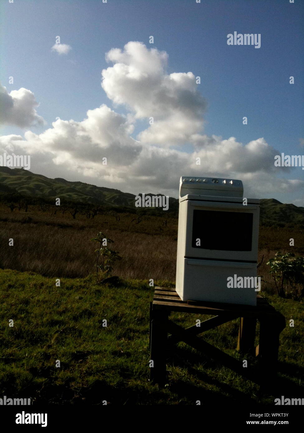 Home Appliance With Table On Grassy Field Against Cloudy Sky During Sunny Day Stock Photo