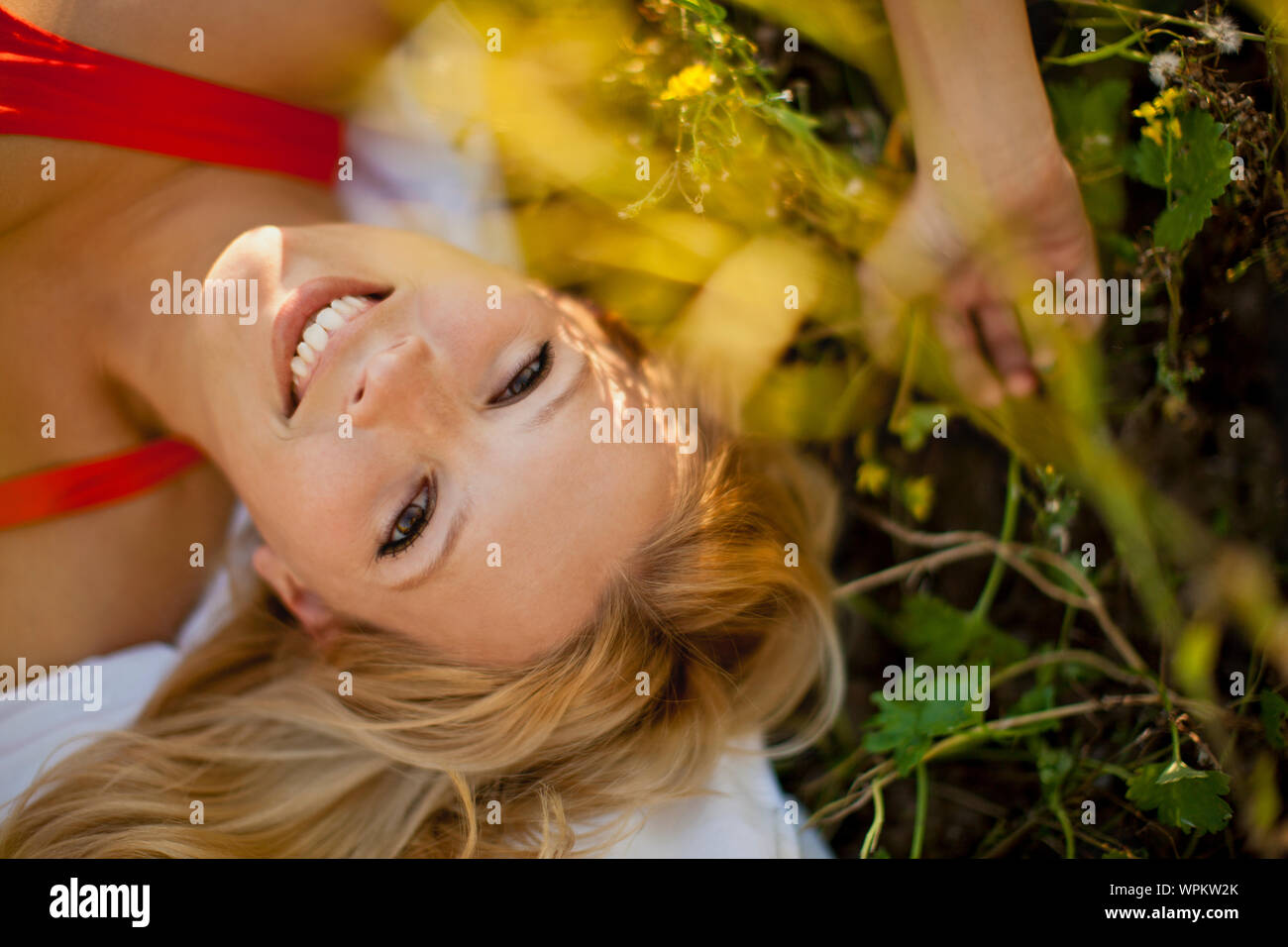 Portrait of woman in a red dress lying in a meadow Stock Photo - Alamy