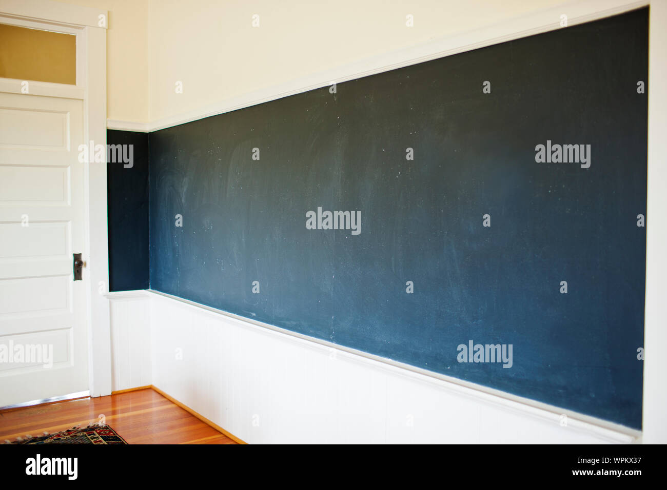 Empty chalkboard covering the wall of a classroom. Stock Photo