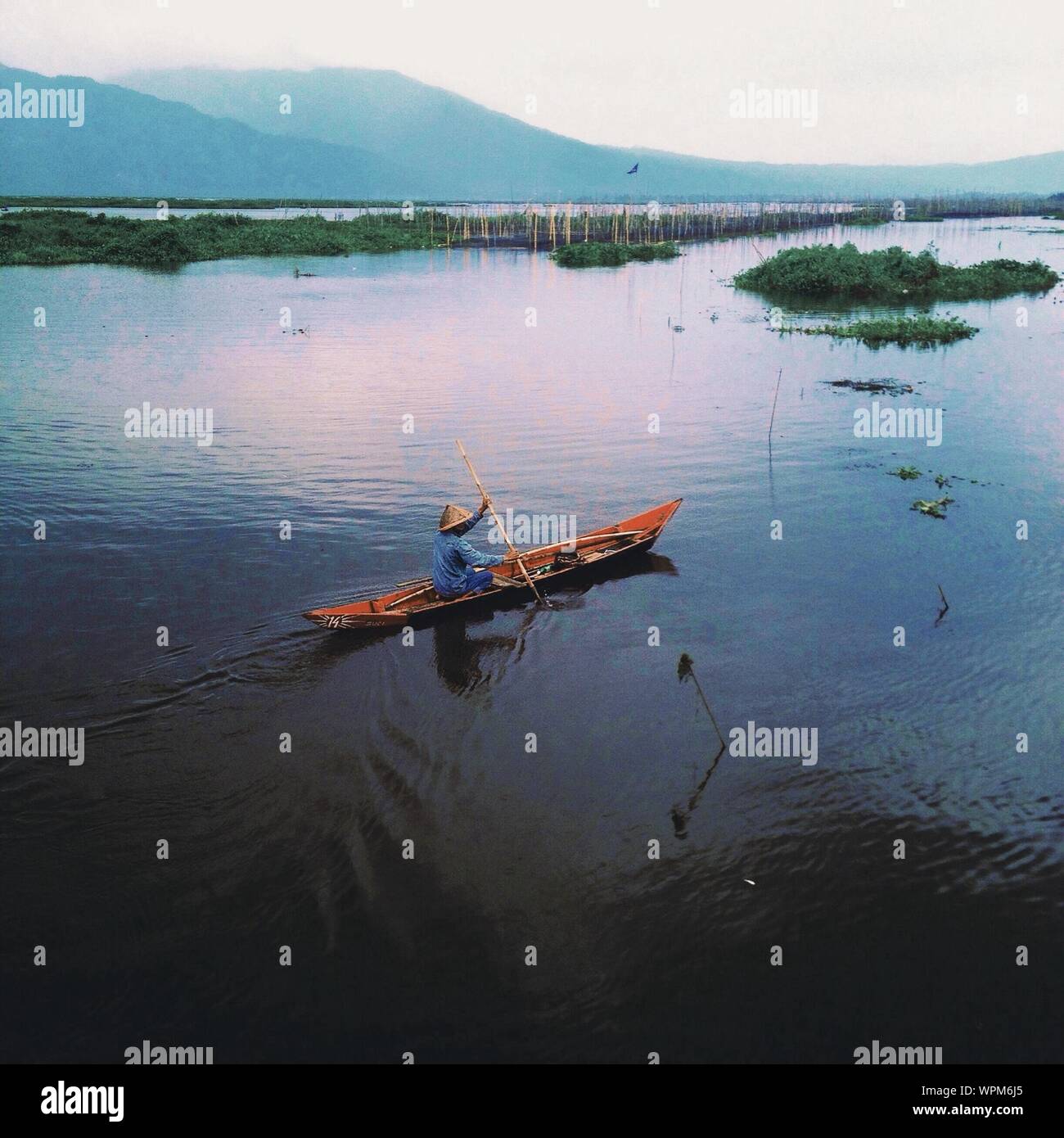 Chinese Man Rowing On Lake Stock Photo