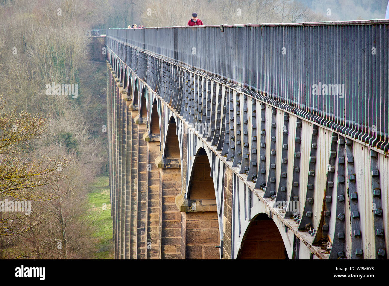 View along the side of the Pontcysyllte Aqueduct carrying the Llangollen canal over the river Dee in Denbighshire Wales with a man in red walking across Stock Photo