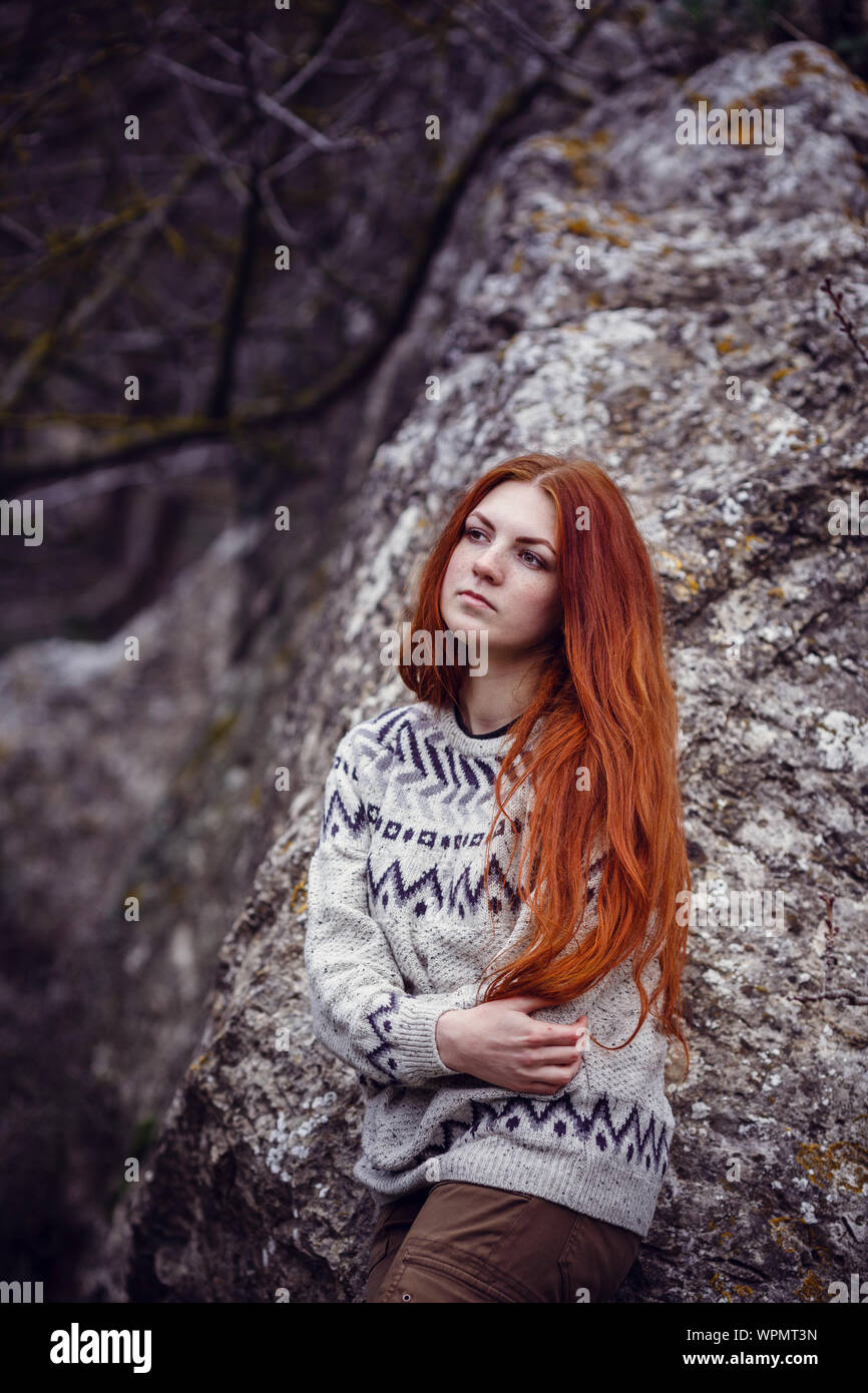 A young woman with red hair is enjoying a walk in nature by the sea. Fall or spring season Stock Photo