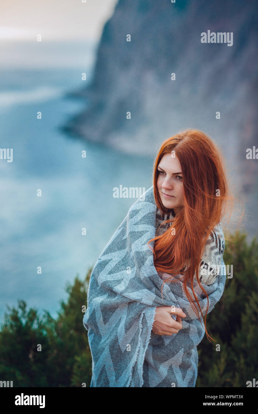 A young woman with red hair is enjoying a walk in nature by the sea. Fall or spring season Stock Photo