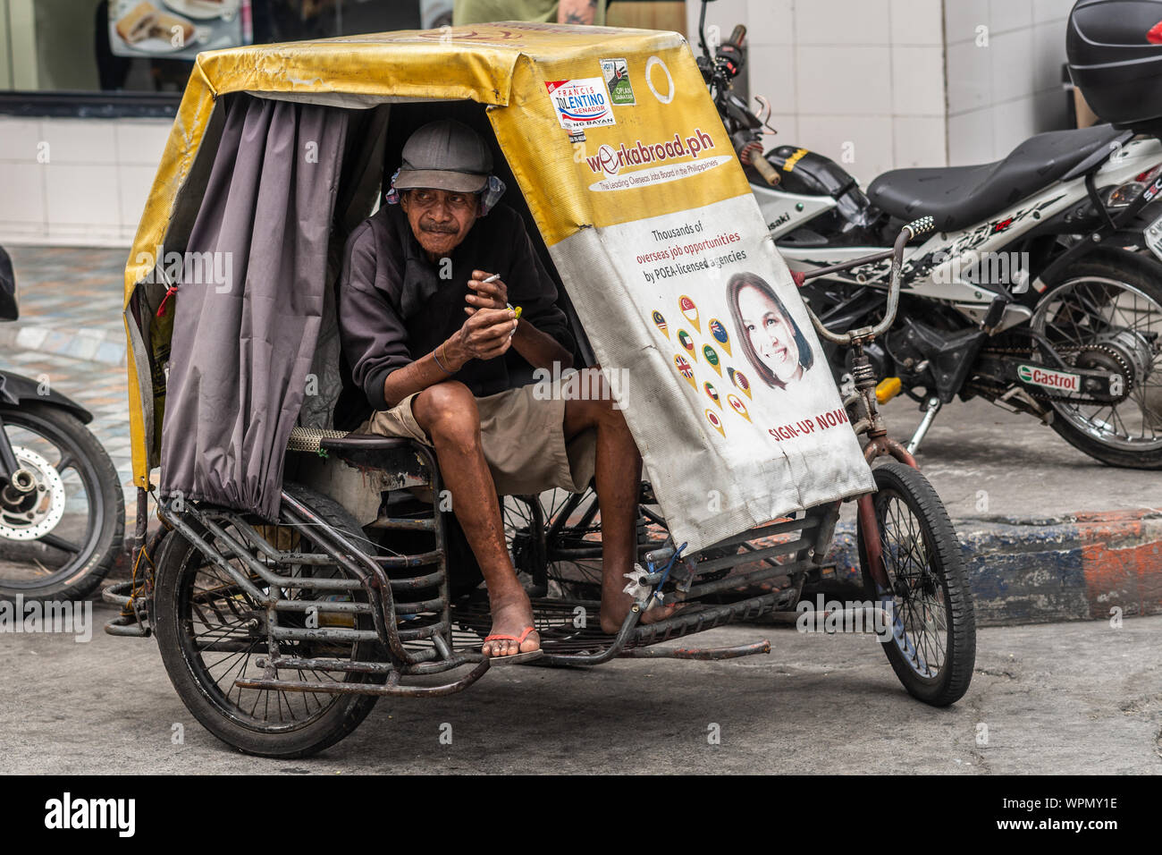 Manila, Philippines - March 5, 2019: Smoking older tricycle cab driver  waits inside his vehicle for customers along street Stock Photo - Alamy