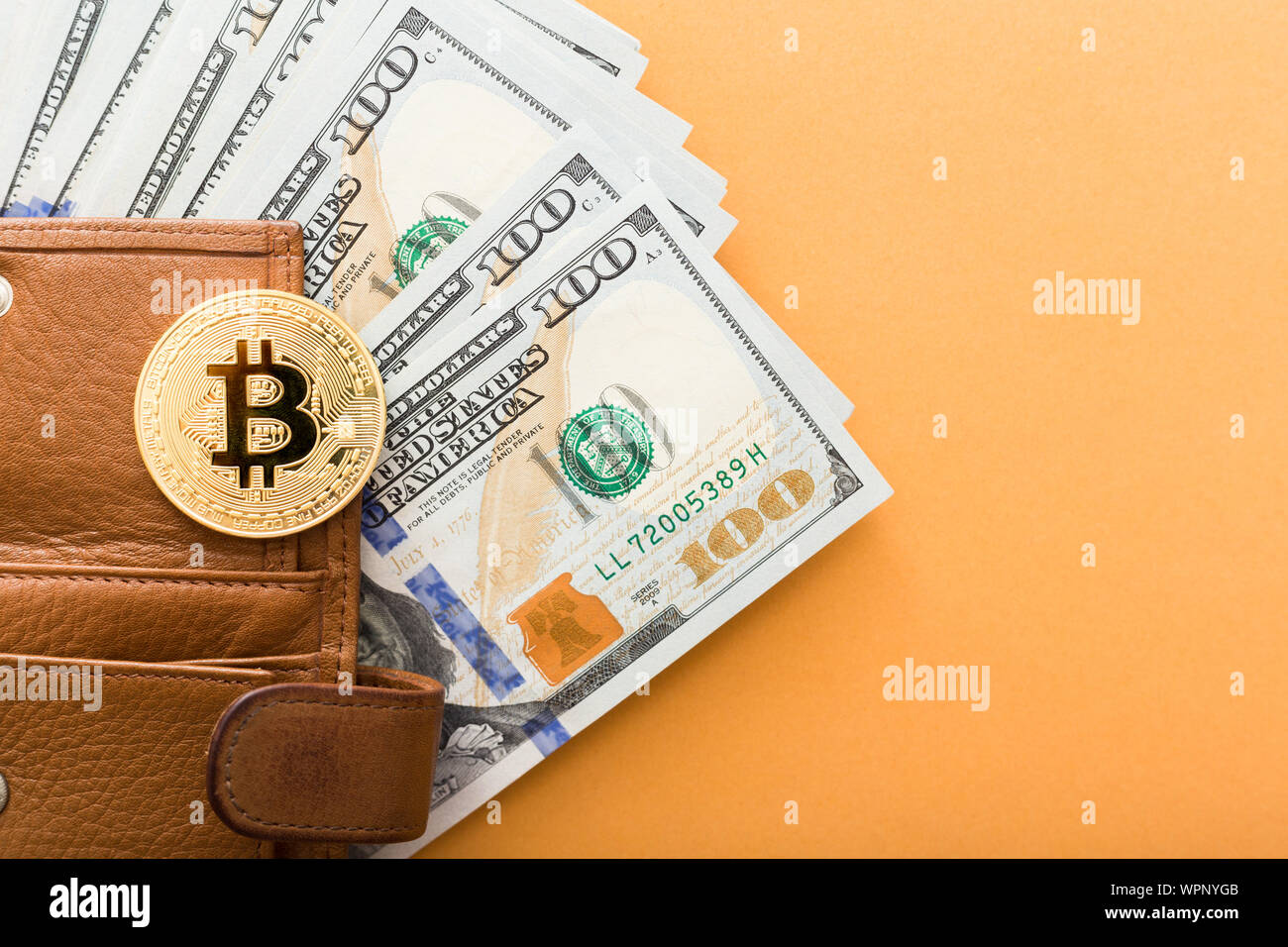 Bitcoin, hundred dollar bills and leather wallet on the orange background  Stock Photo - Alamy