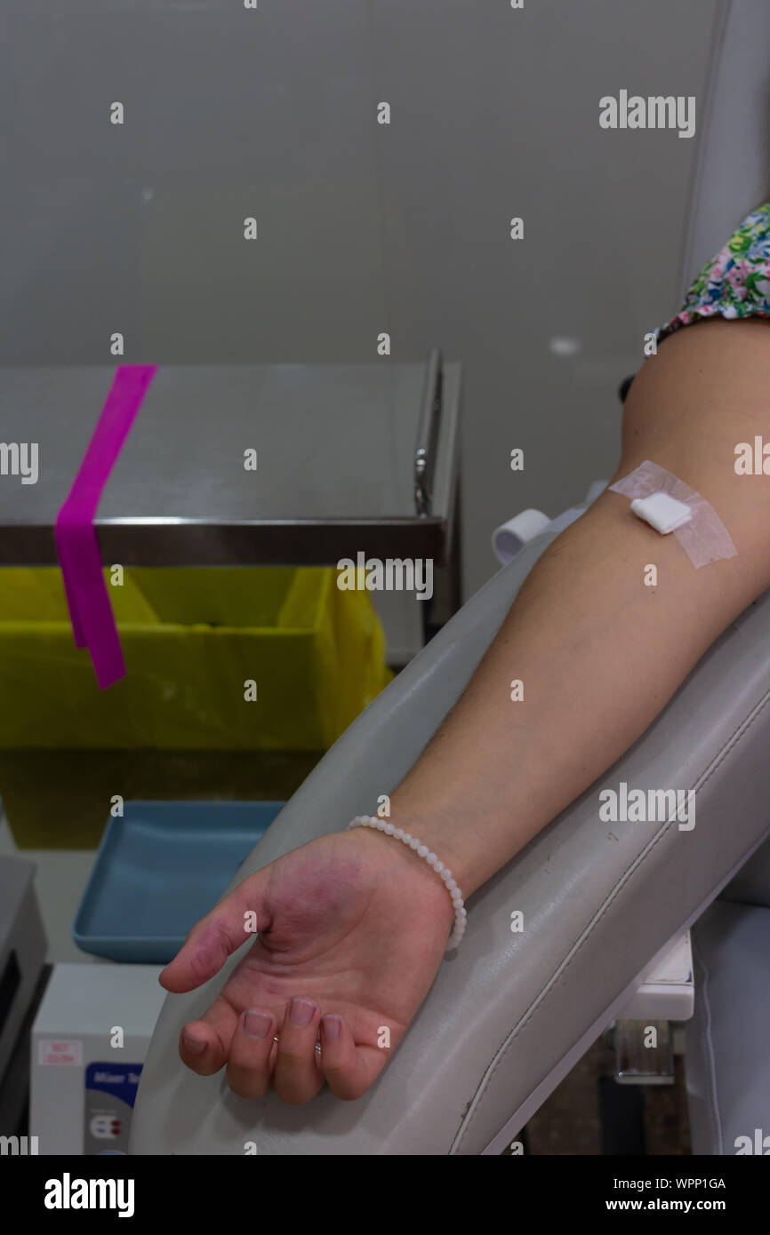 Woman's arm with gauze and adhesive after donating blood in a blood