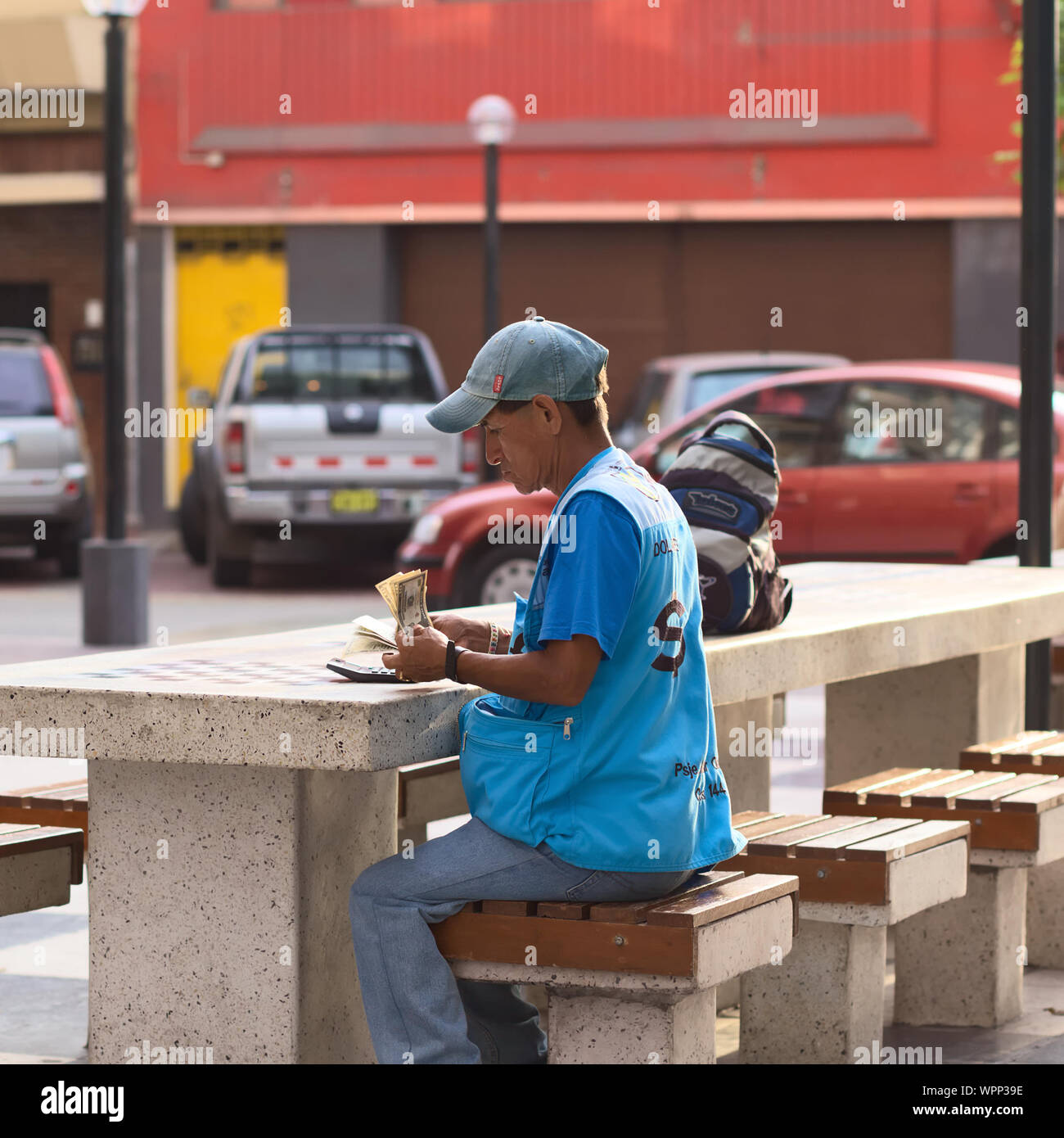 LIMA, PERU - MARCH 5, 2012: Unidentified street money exchanger counting dollar bills at an outdoor table in Miraflores on March 5, 2012 in Lima, Peru Stock Photo