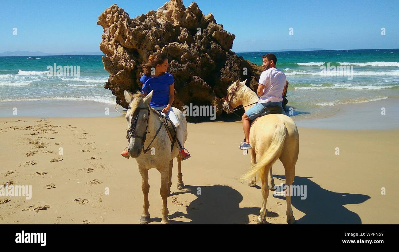 Man And Woman Riding Horses At Beach Stock Photo