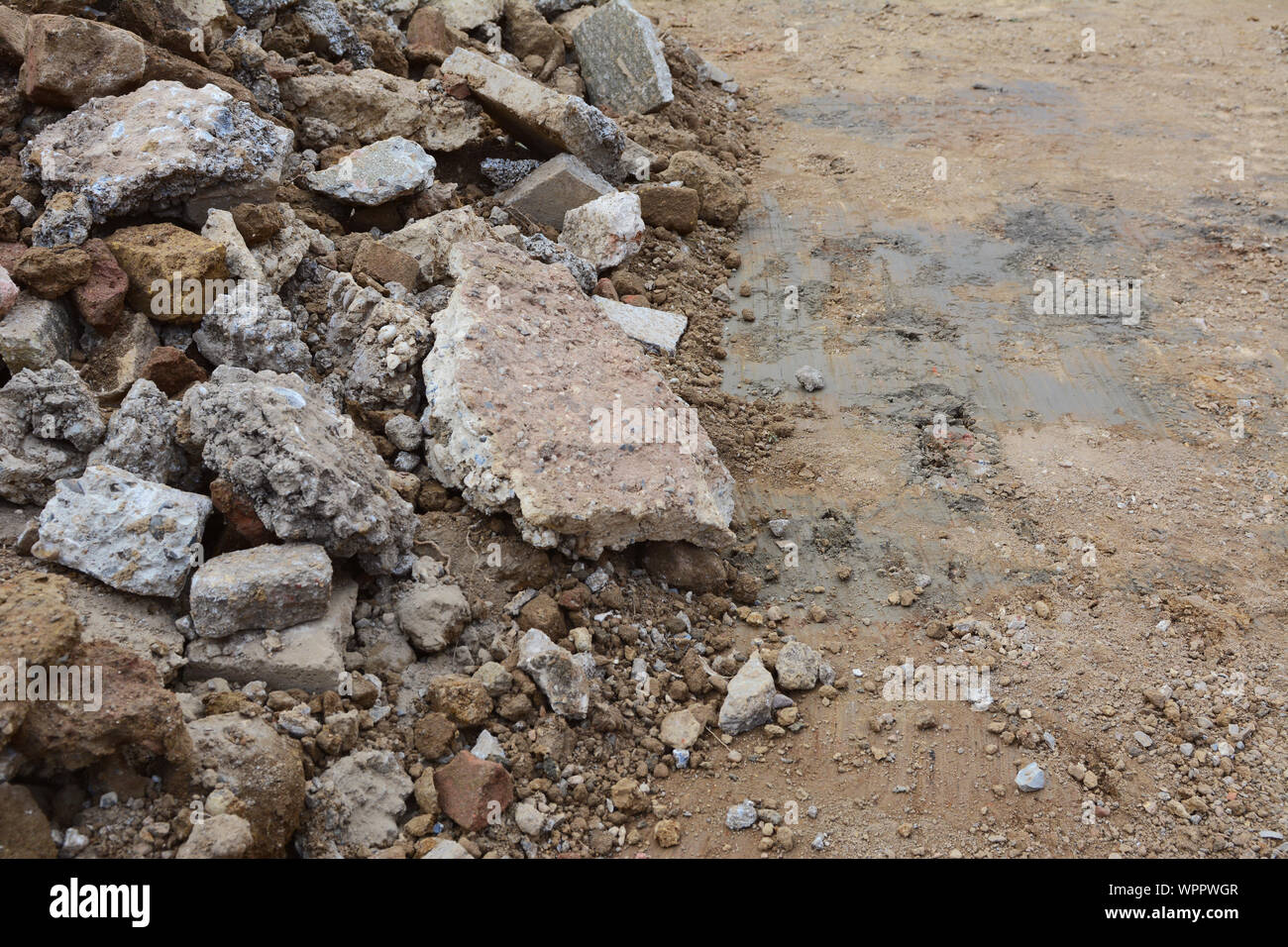 Large broken pieces of rough concrete, bricks and paving slabs next to smooth excavated ground with copy space Stock Photo