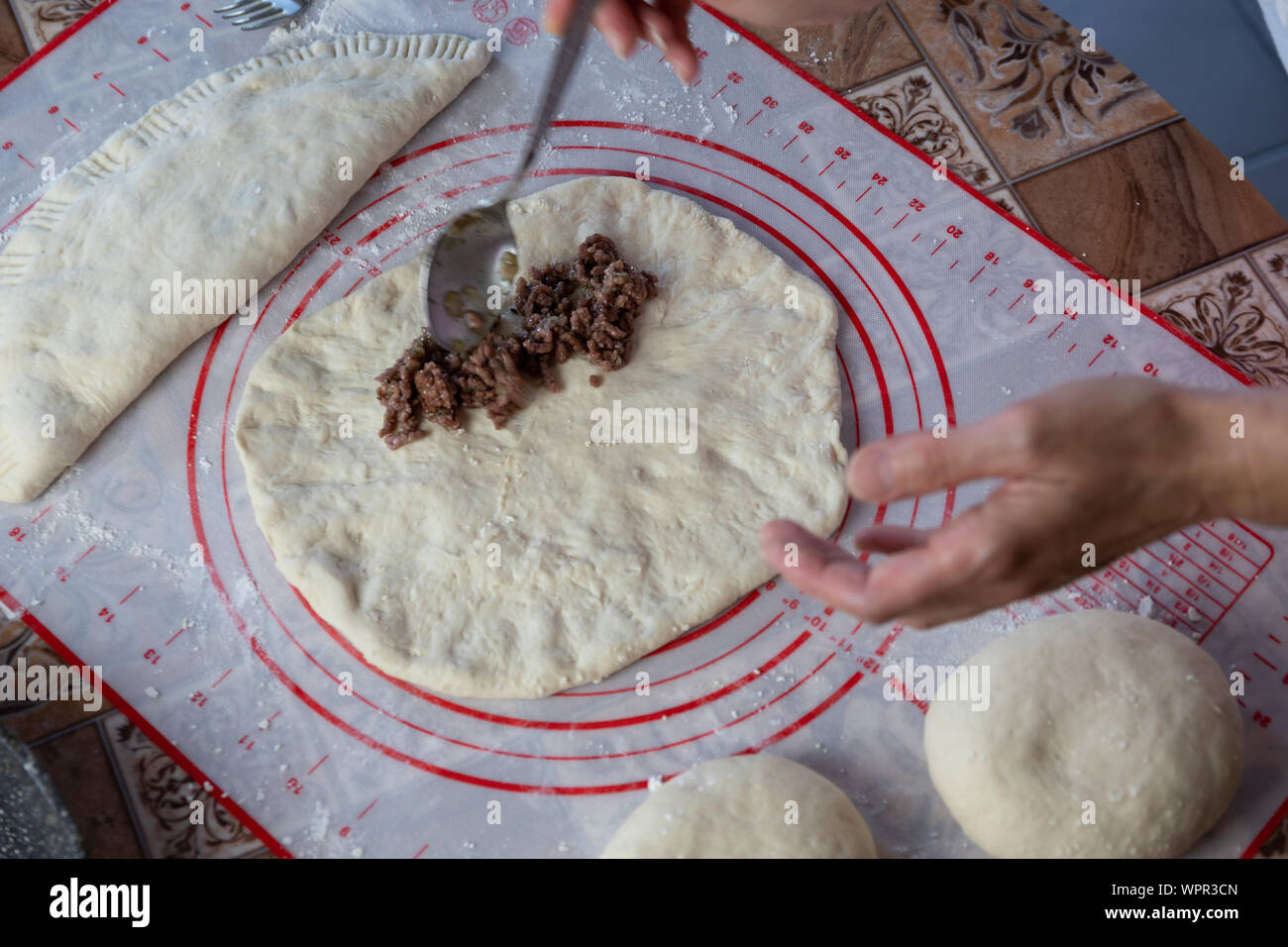Close up of a woman's hands making dough for homemade bread, empanadas. female baker preparing bread on a silicone baking sheet Stock Photo