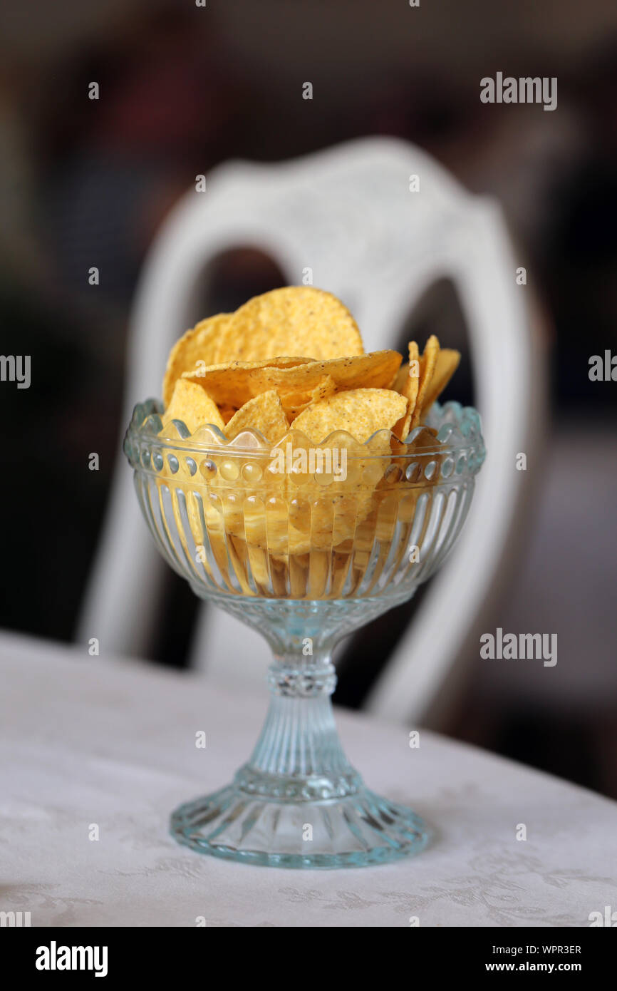 Chips and dry bread bites in beautiful glass bowls. Crunchy and delicious snacks served in a Finnish home. Closeup still life photo, a soft background. Stock Photo