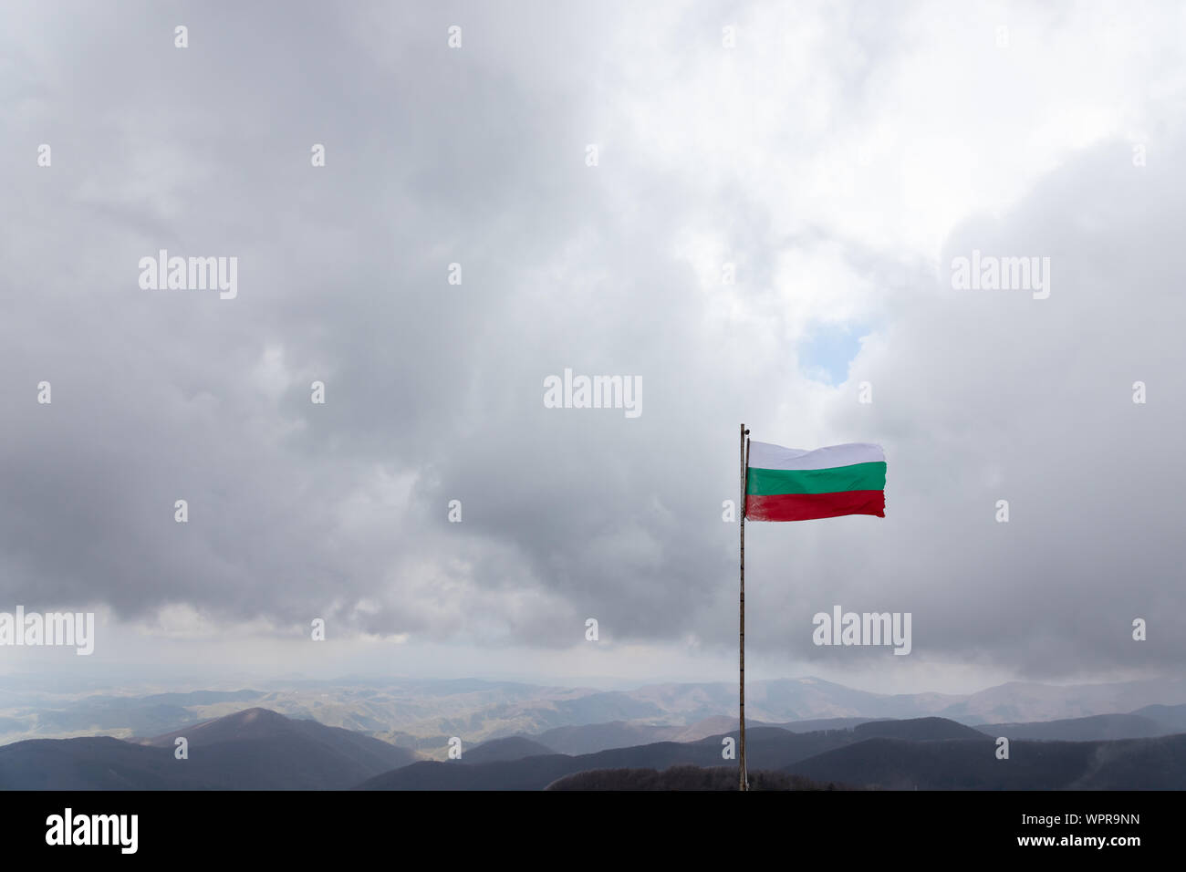 Frozen waving bulgarian flag with a beautiful view of stara planina, the biggest mountain of Bulgaria Stock Photo