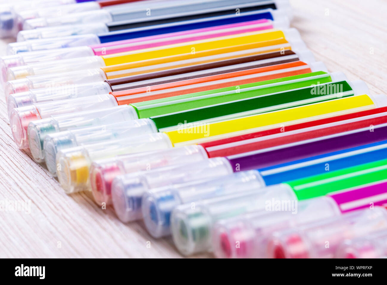 Multi-colored markers on a white wooden chtol, top view, place for text Stock Photo