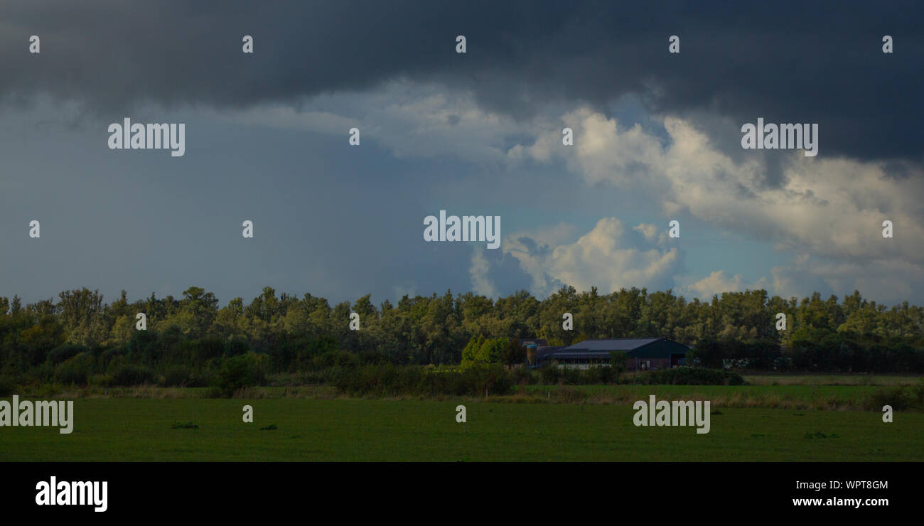 Calm before the storm, cloud above a farm in a Dutch landscape Stock Photo