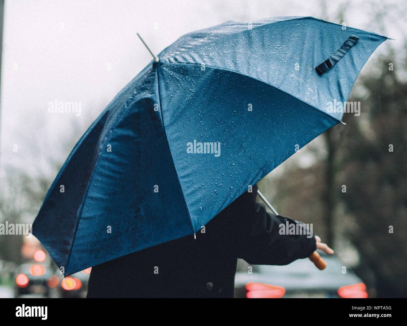 Person holding an umbrella in rain hires stock photography and images