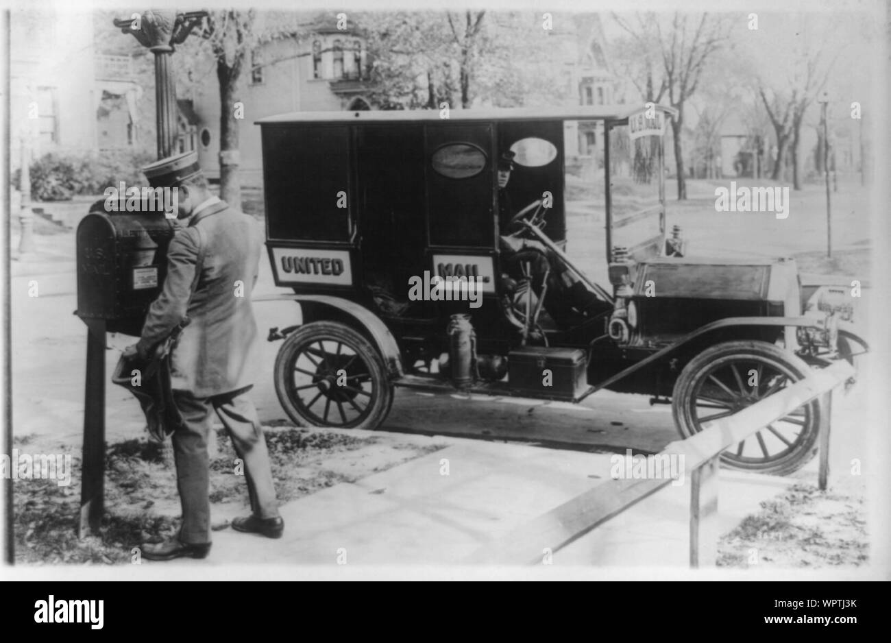 Mailman emptying mailbox, automobile marked United Mail at curb Stock ...