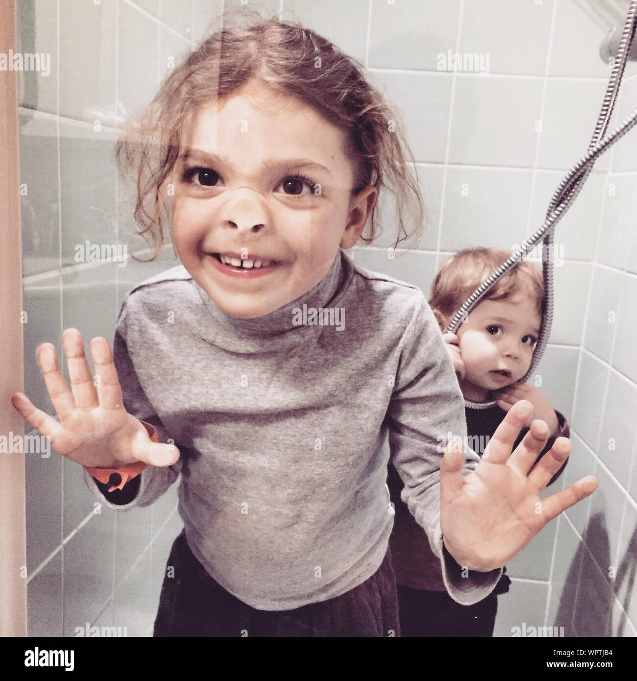 Close up Of Girl And Boy In Bathroom Seen Through Glass Window Stock
