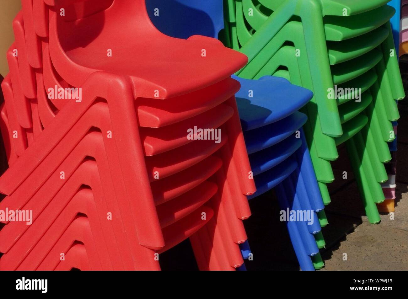 Stack Of Multi Colored Chairs During Sunny Day Stock Photo