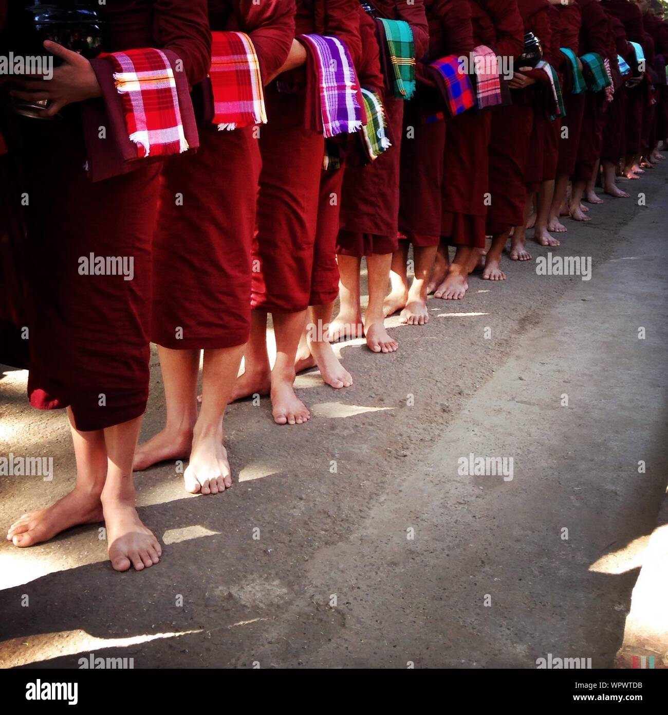 Low Section Of Monks Standing In Line On Street Stock Photo