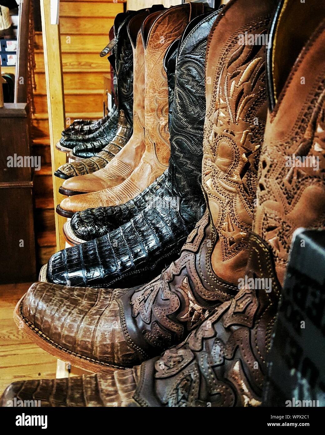 Various Cowboy Boots On Shelf For Sale At Store Stock Photo