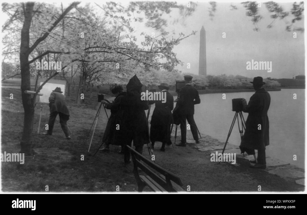 Man with easel and group of photographers at the Tidal Basin facing the Washington Monument in the background, with cherry trees in blossom, Washington, D.C. Stock Photo