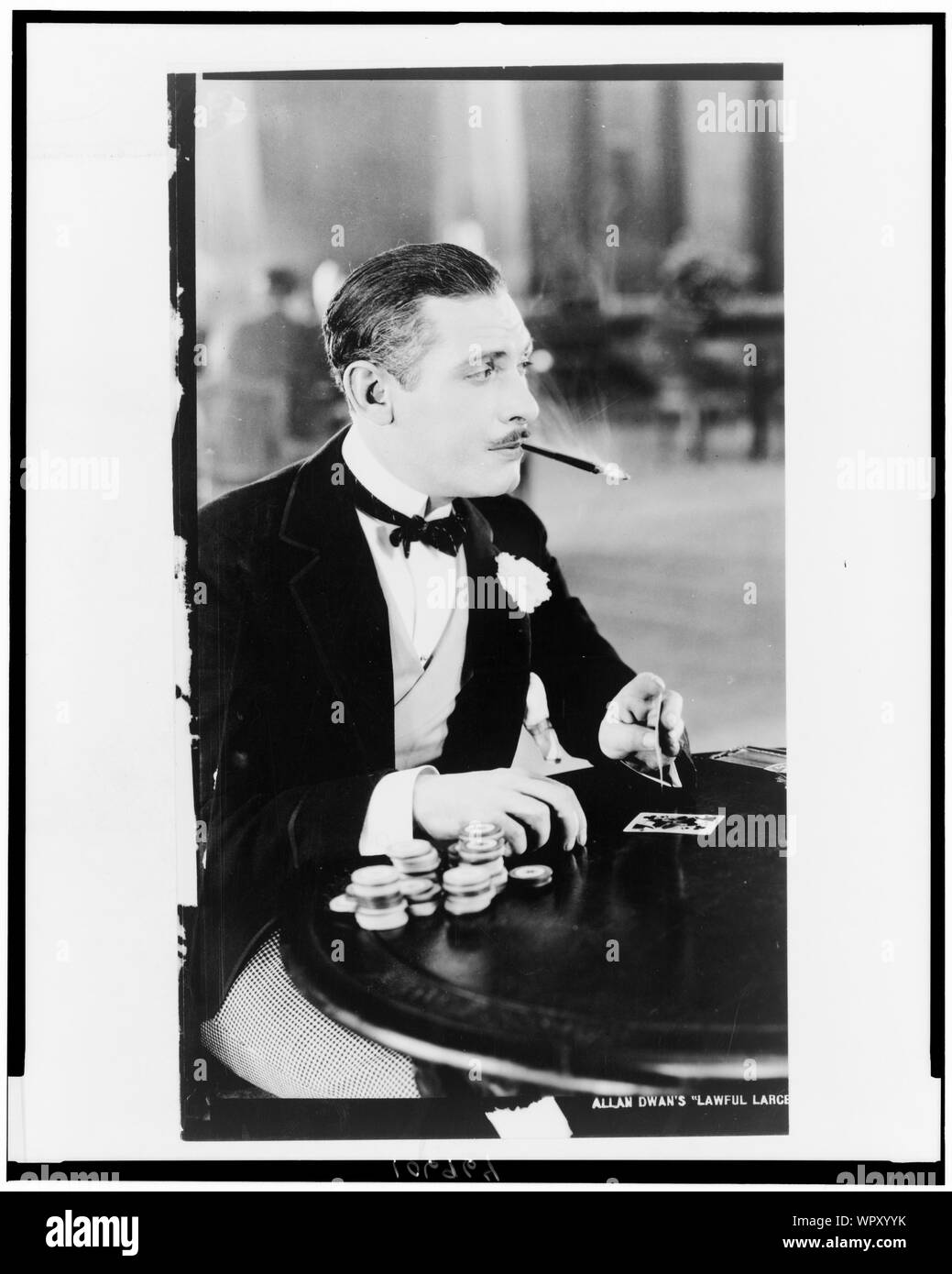 Man, with cigarette holder in mouth, playing cards Stock Photo