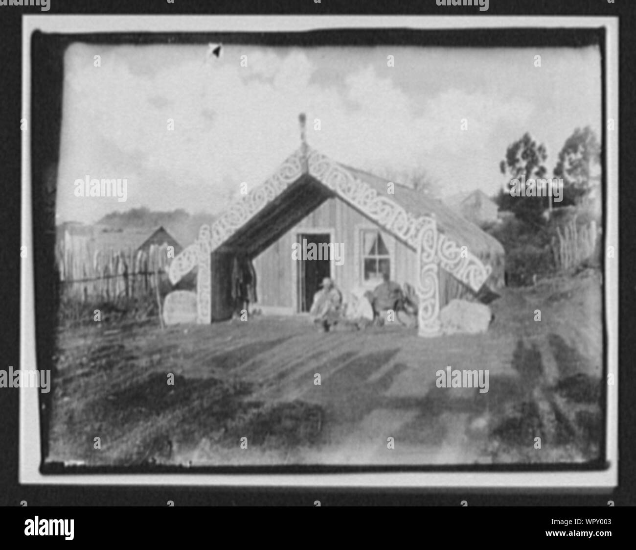 Man, woman and baby in front of ornamented Maori house Stock Photo