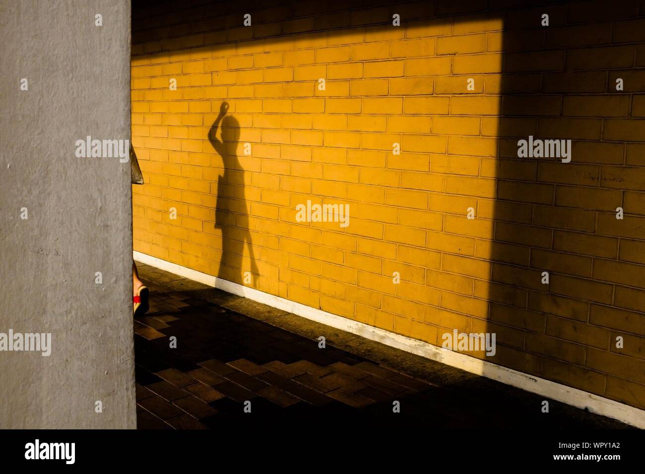 Shadow Of Person On Yellow Brick Wall Stock Photo
