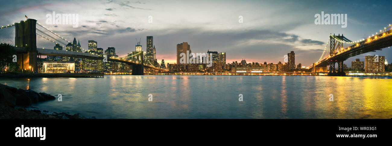 Panoramic View Of Illuminated Suspension Bridges And Manhattan Skyline Stock Photo