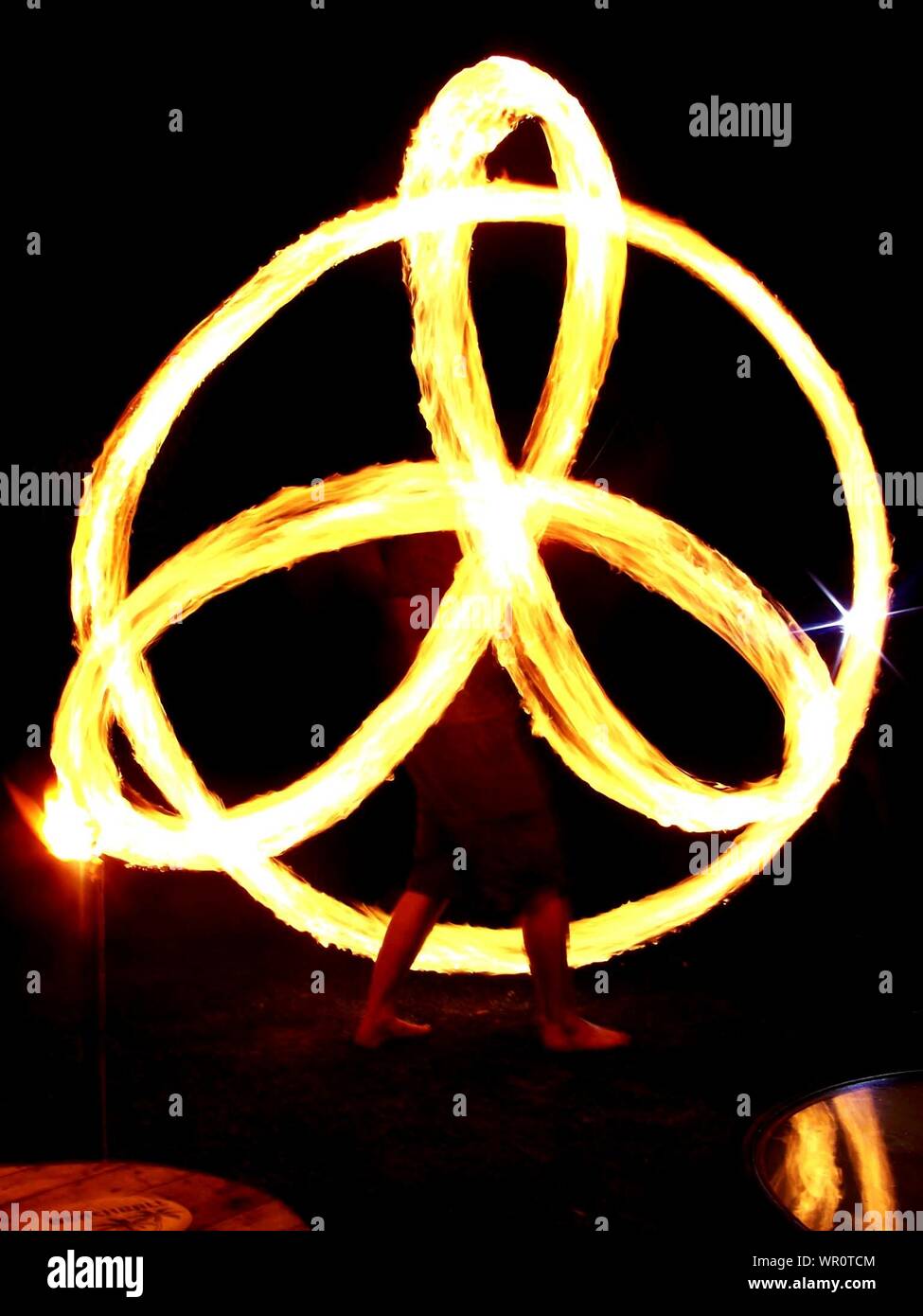 Low Section Of Person Performing Fire Poi At Night Stock Photo