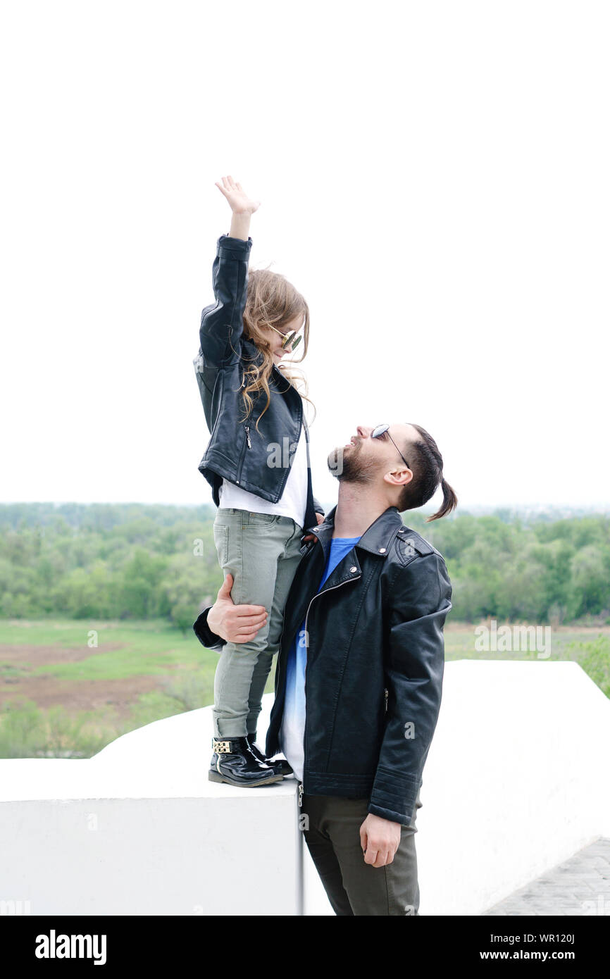 Fashionable stylish family for a walk. Charming schoolchild and her handsome young dad spend time together outdoors. Family look. Urban casual outfit. Stock Photo