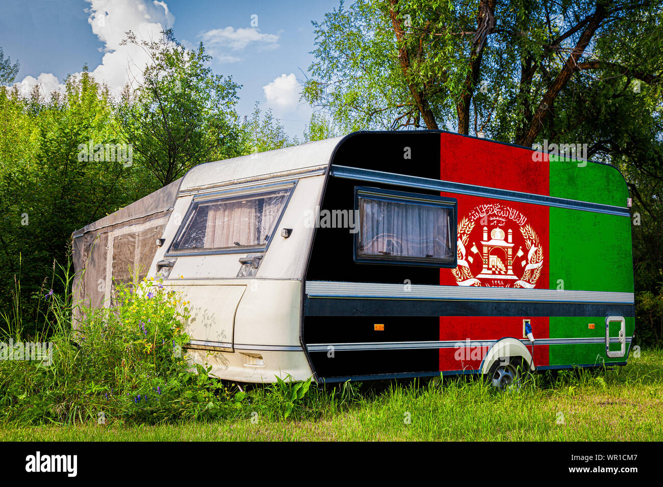 A car trailer, a motor home, painted in the national flag of  Afghanistan stands parked in a mountainous. The concept of road transport, trade, export Stock Photo