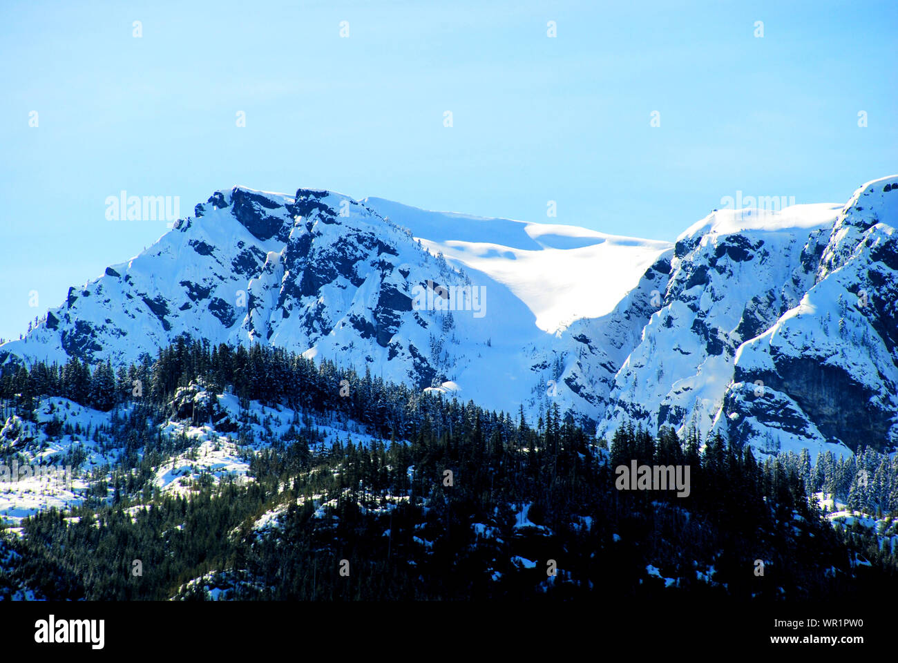 Snowy mountain cap with forest, clouds and sky, near Squamish, British Columbia, Canada, seen from Stawamus Chief mountain Stock Photo