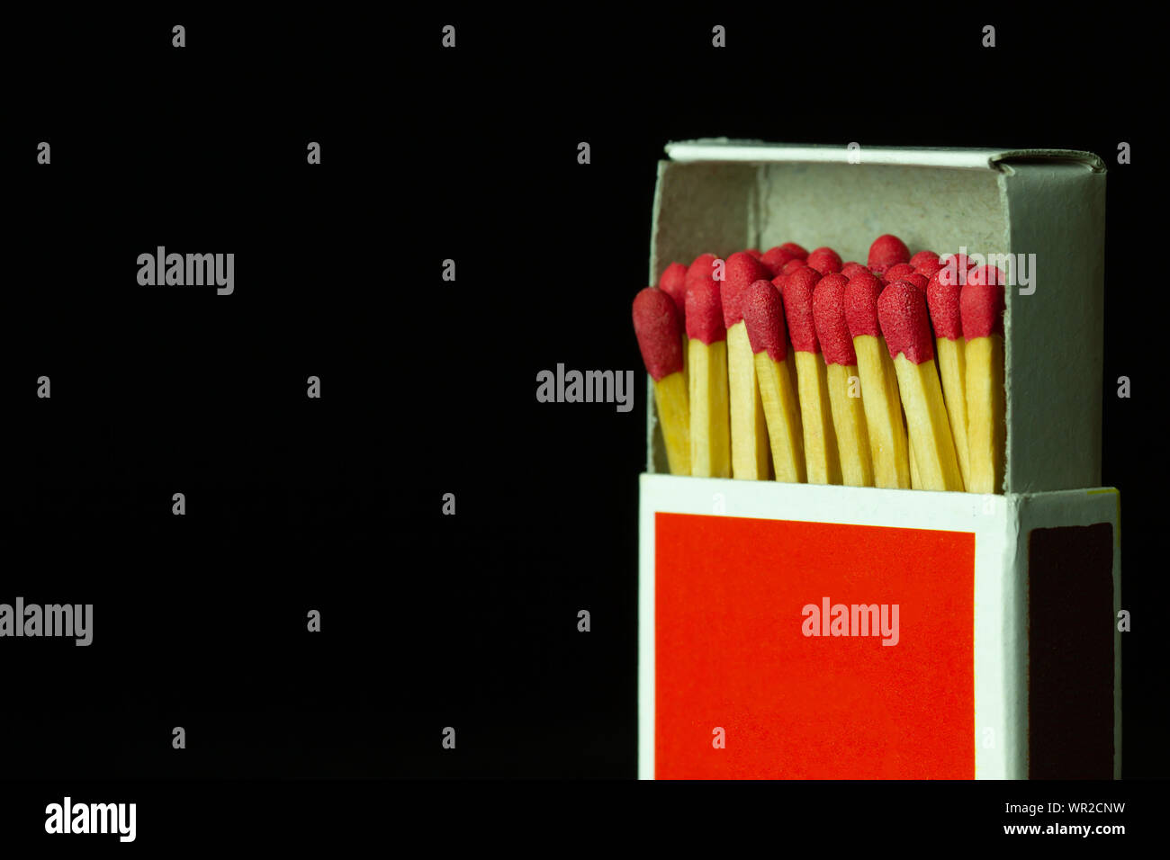 Matches stick in red paper box on black background. Closeup and copy space. Stock Photo