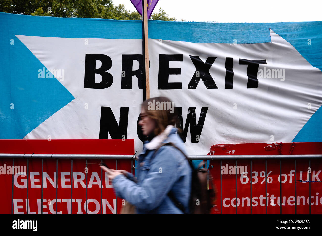 London, UK. 09th Sep, 2019. A woman walks past a Brexit Party banner calling for 'Brexit Now' outside the Houses of Parliament in London on the day of the prorogation of the parliamentary session, which will see parliamentary activities suspended until mid-October. Credit: SOPA Images Limited/Alamy Live News Stock Photo