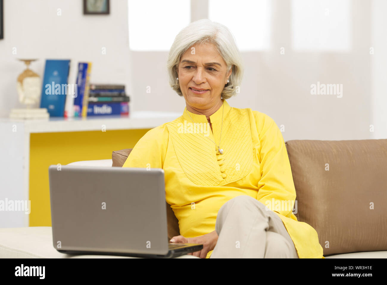 Senior woman sitting on couch in living room Stock Photo - Alamy