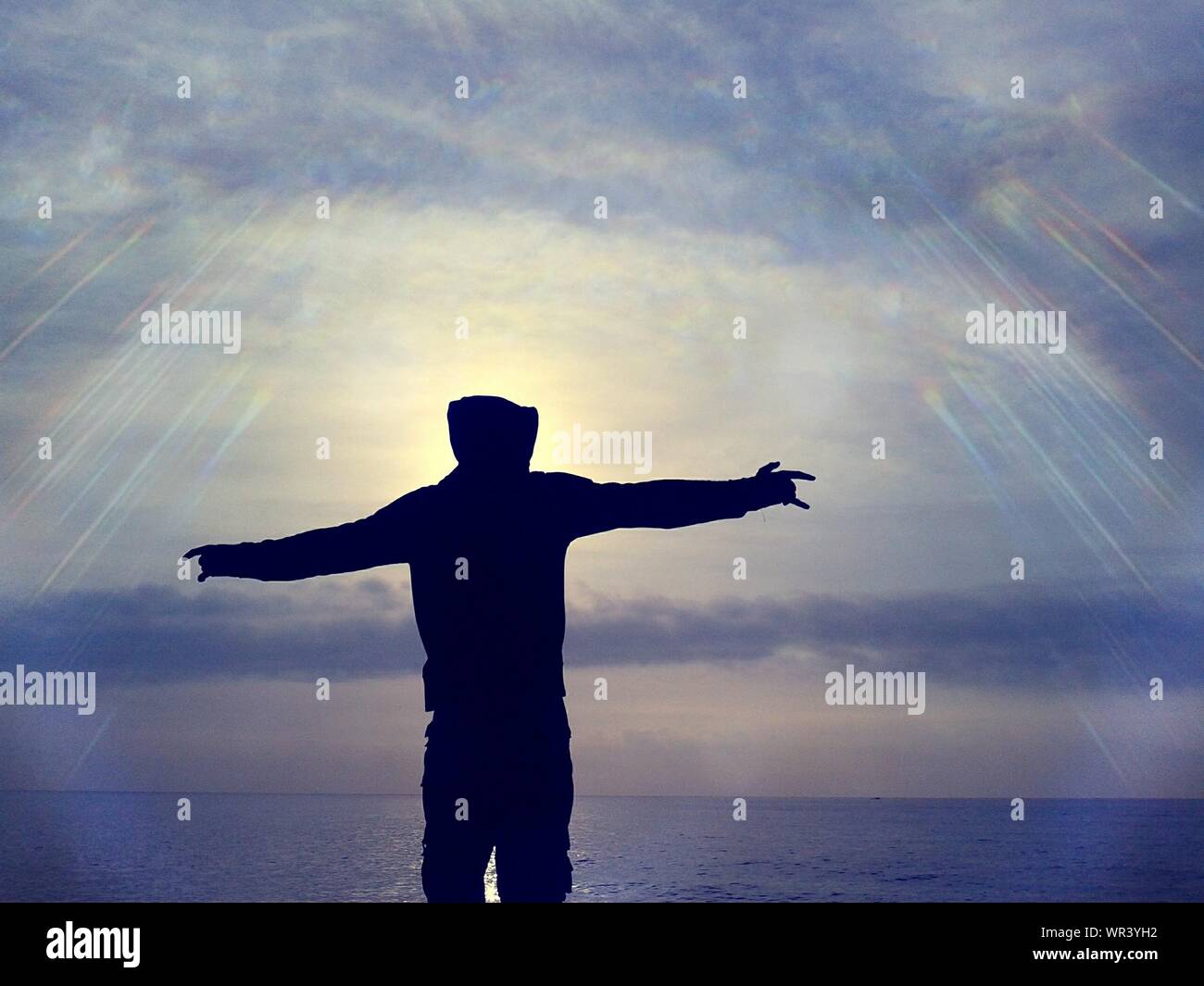 Silhouette Of Man With Outstretched Arms At Beach Stock Photo